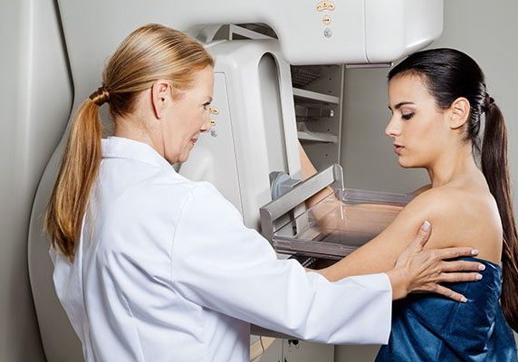 Doctor Assisting Patient Undergoing Mammogram Mature female doctor assisting young patient undergoing mammogram